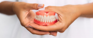 woman holding dentures in hands - smile makeover